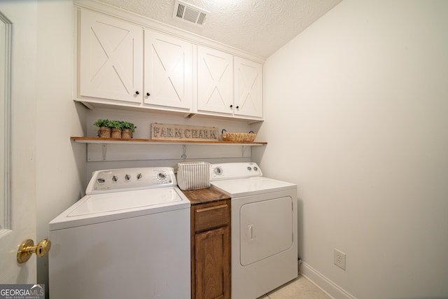 washroom with cabinets, a textured ceiling, and washer and clothes dryer