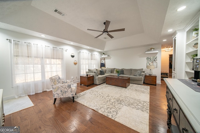 living room with hardwood / wood-style flooring, a textured ceiling, a raised ceiling, and ceiling fan