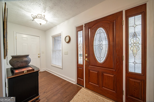 foyer entrance with a textured ceiling and dark hardwood / wood-style floors