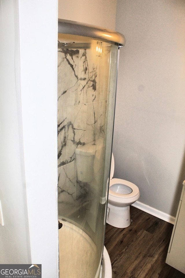 bathroom featuring toilet, a shower with door, and hardwood / wood-style floors