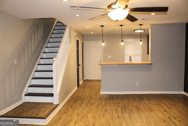 unfurnished living room featuring ceiling fan, sink, and wood-type flooring