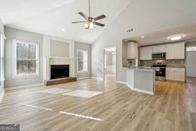 kitchen with kitchen peninsula, stainless steel appliances, light wood-type flooring, a fireplace, and white cabinets