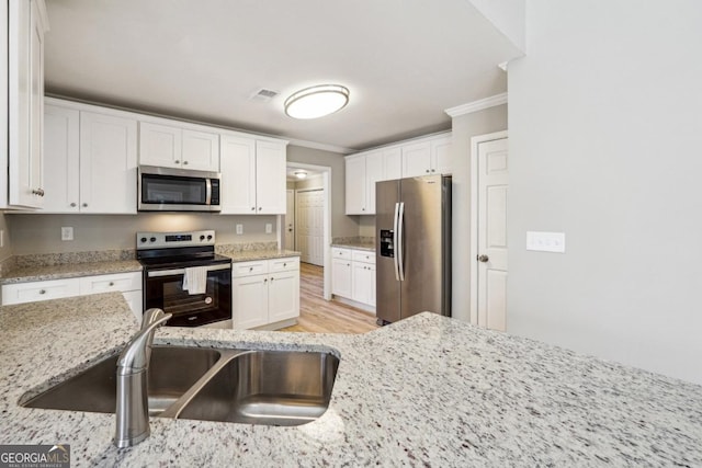 kitchen with appliances with stainless steel finishes, light stone countertops, crown molding, white cabinets, and sink