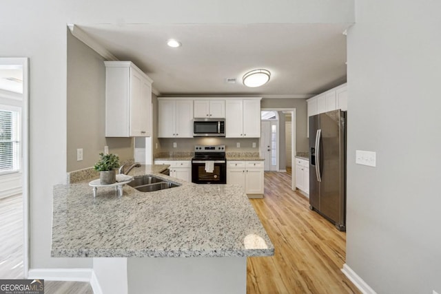 kitchen with white cabinetry, kitchen peninsula, appliances with stainless steel finishes, light stone counters, and sink