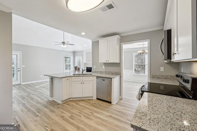 kitchen with white cabinets, kitchen peninsula, ceiling fan with notable chandelier, and stainless steel appliances