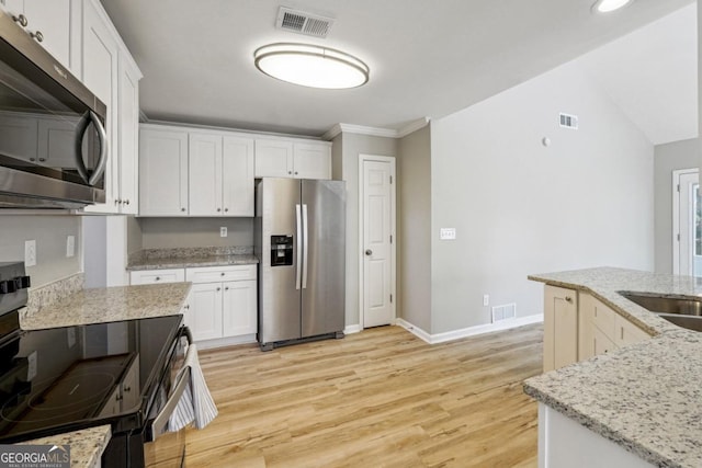 kitchen with white cabinets, stainless steel appliances, light stone counters, light hardwood / wood-style flooring, and crown molding