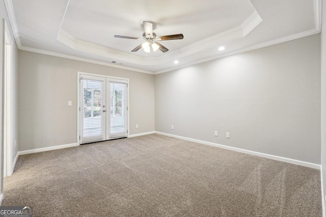 carpeted empty room with ornamental molding, french doors, and a tray ceiling