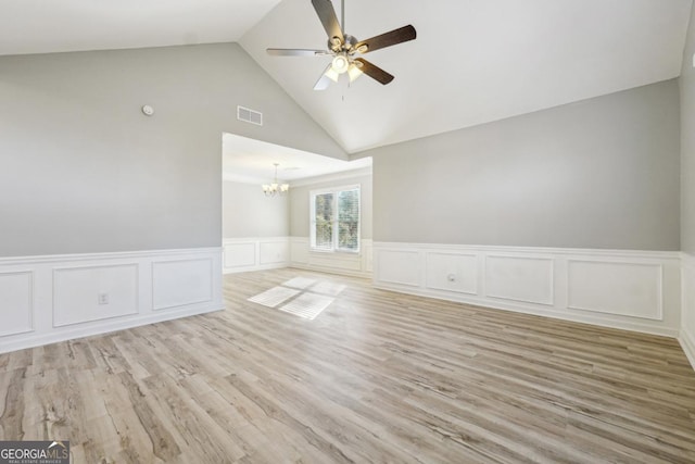 unfurnished room with ceiling fan with notable chandelier, light hardwood / wood-style flooring, and high vaulted ceiling