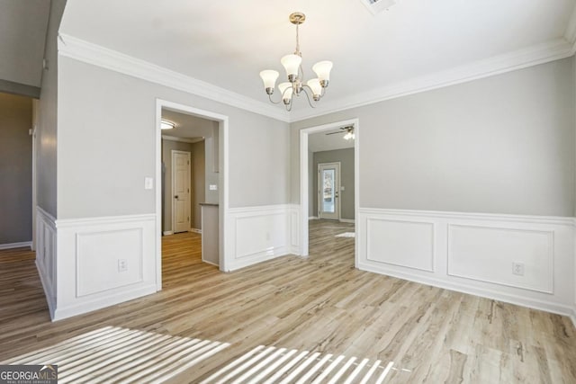 empty room featuring ceiling fan with notable chandelier, light hardwood / wood-style floors, and crown molding