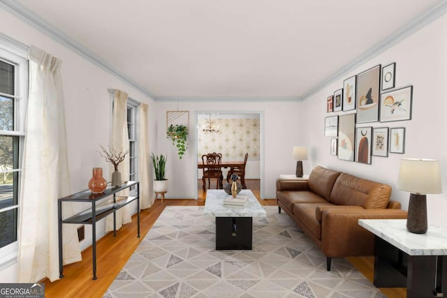 living room with wood-type flooring, ornamental molding, and a chandelier