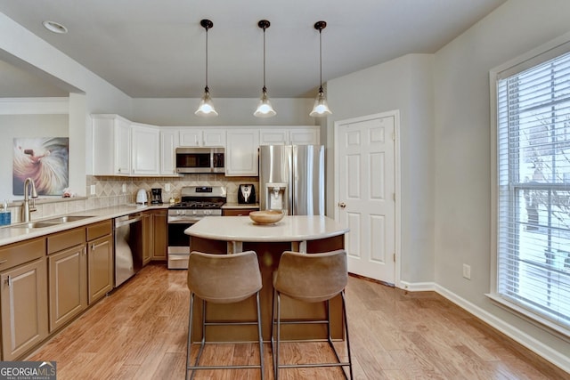 kitchen with tasteful backsplash, pendant lighting, sink, a breakfast bar area, and stainless steel appliances