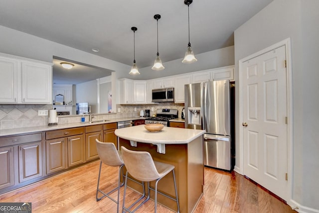 kitchen with a kitchen bar, kitchen peninsula, appliances with stainless steel finishes, decorative backsplash, and white cabinets