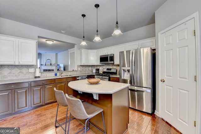 kitchen featuring white cabinets, a kitchen island, stainless steel appliances, decorative backsplash, and a kitchen breakfast bar