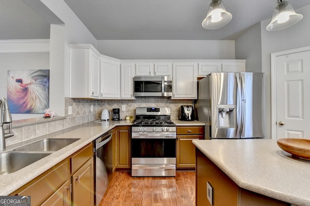 kitchen featuring appliances with stainless steel finishes, decorative backsplash, light wood-type flooring, white cabinets, and sink