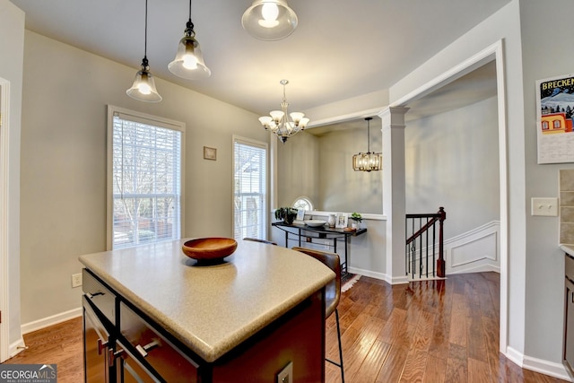 kitchen with a center island, decorative light fixtures, ornate columns, a chandelier, and hardwood / wood-style flooring