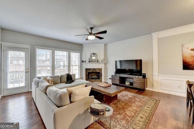 living room with a premium fireplace, dark wood-type flooring, and ceiling fan