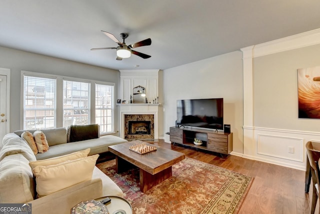 living room with ceiling fan, wood-type flooring, and a premium fireplace