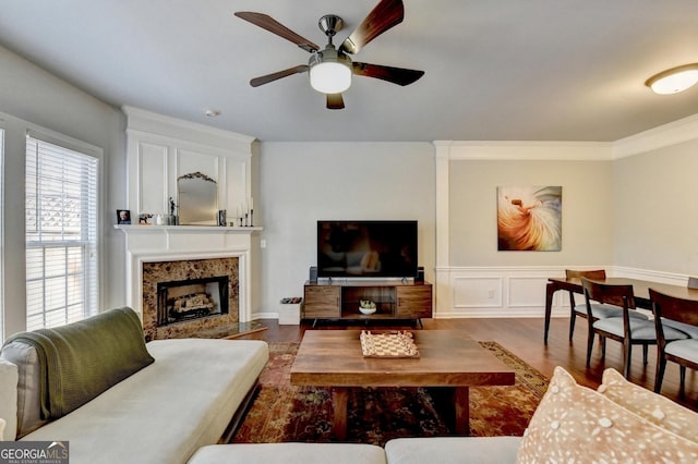 living room with ceiling fan, dark wood-type flooring, crown molding, and a premium fireplace