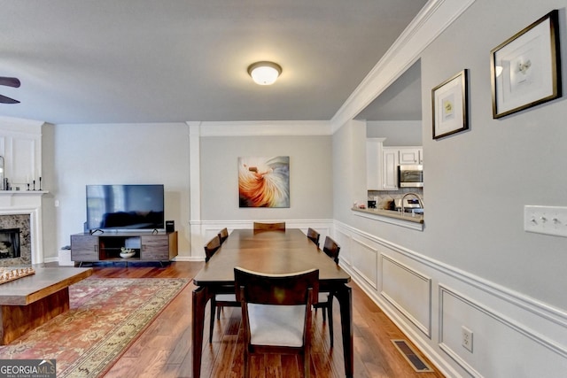 dining room featuring dark wood-type flooring, a high end fireplace, and crown molding