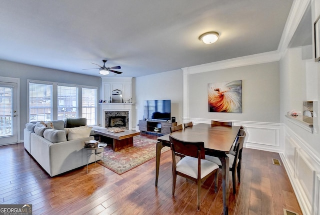 living room with ceiling fan, plenty of natural light, ornamental molding, and dark wood-type flooring