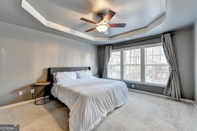 carpeted bedroom featuring ceiling fan and a tray ceiling