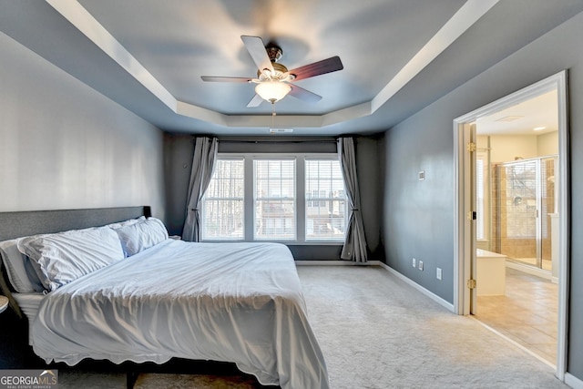 carpeted bedroom featuring ceiling fan, connected bathroom, and a tray ceiling