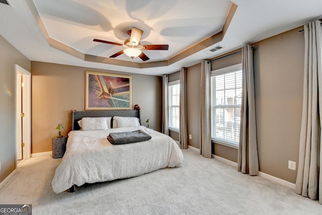 carpeted bedroom featuring ceiling fan and a tray ceiling