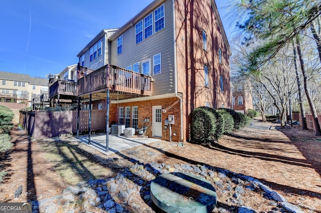 rear view of house featuring a wooden deck and a patio