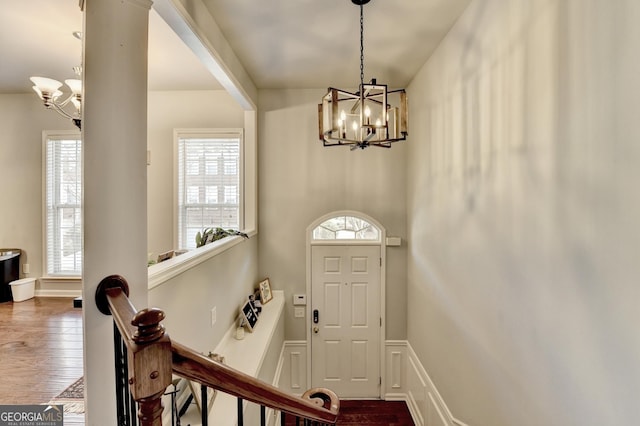 entryway with an inviting chandelier, a wealth of natural light, and wood-type flooring