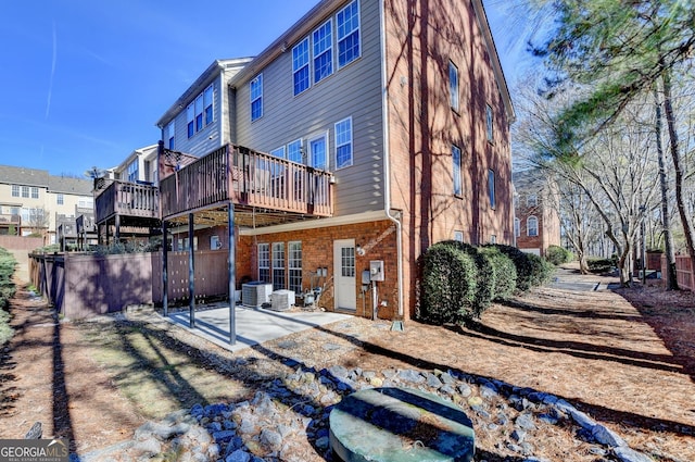 rear view of property featuring a wooden deck and a patio