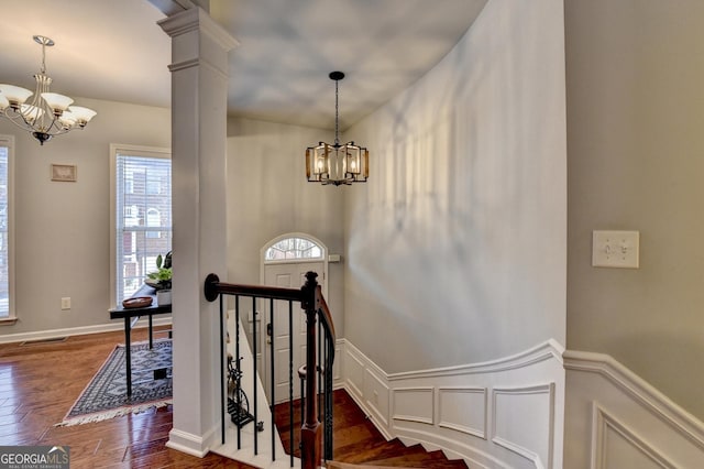 stairway with wood-type flooring, ornate columns, and a chandelier