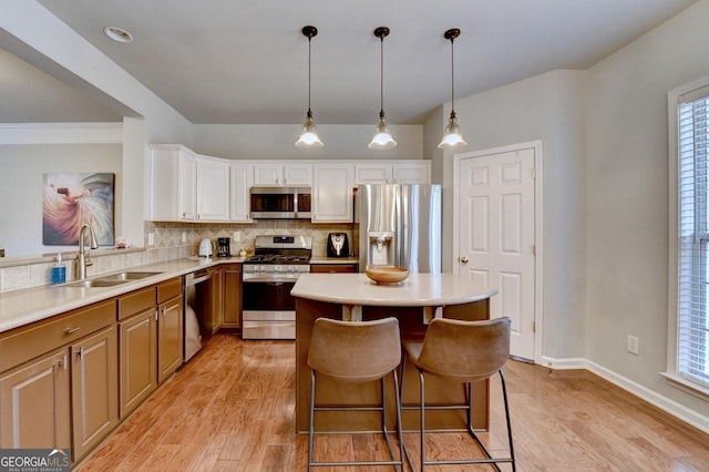 kitchen with tasteful backsplash, pendant lighting, a breakfast bar, sink, and stainless steel appliances