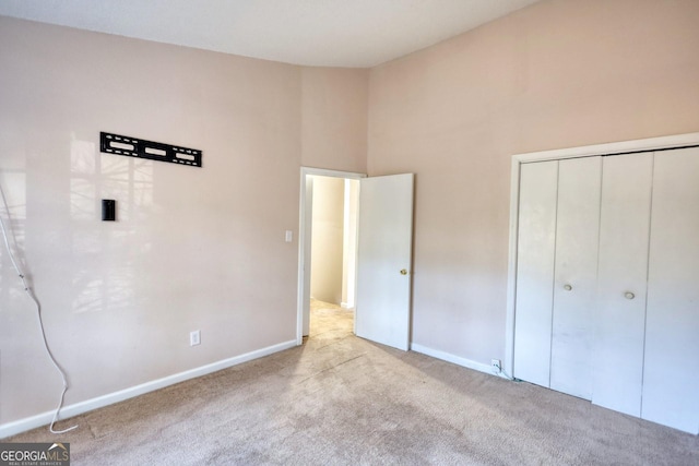 unfurnished bedroom featuring light colored carpet, a closet, and a towering ceiling