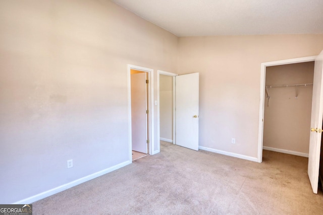 unfurnished bedroom featuring lofted ceiling, a closet, and light carpet