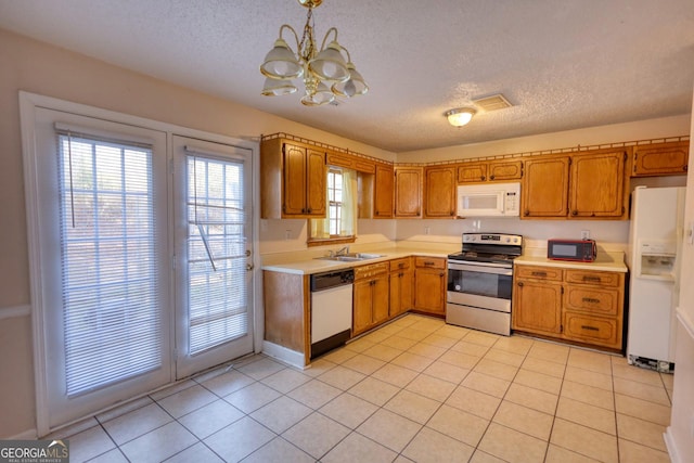 kitchen featuring sink, white appliances, a textured ceiling, and pendant lighting