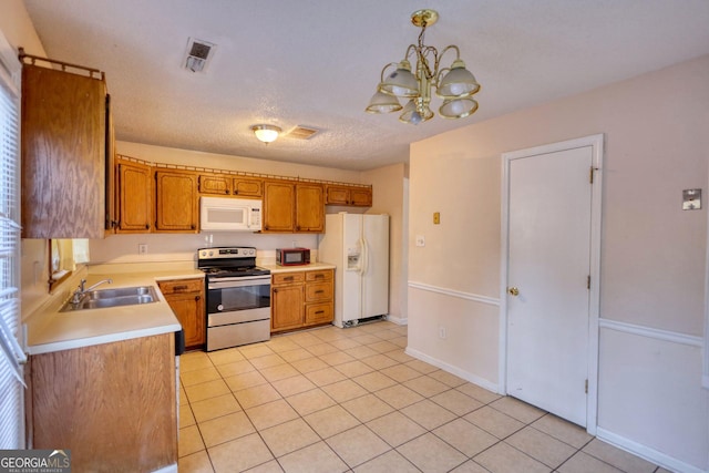 kitchen with white appliances, sink, hanging light fixtures, a chandelier, and light tile patterned floors