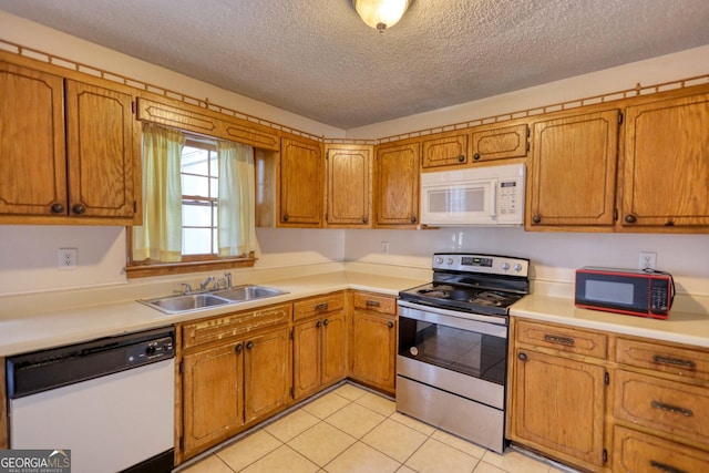 kitchen featuring a textured ceiling, light tile patterned floors, sink, and white appliances