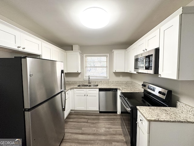 kitchen featuring sink, white cabinetry, light stone countertops, dark wood-type flooring, and stainless steel appliances