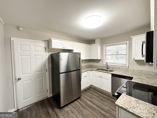 kitchen with sink, dark wood-type flooring, stainless steel appliances, white cabinets, and light stone counters