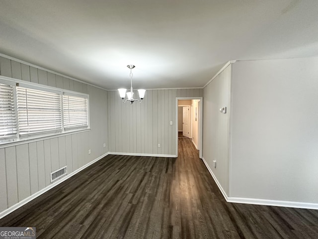 spare room featuring dark wood-type flooring, an inviting chandelier, and ornamental molding