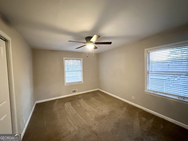 spare room featuring ceiling fan and dark carpet