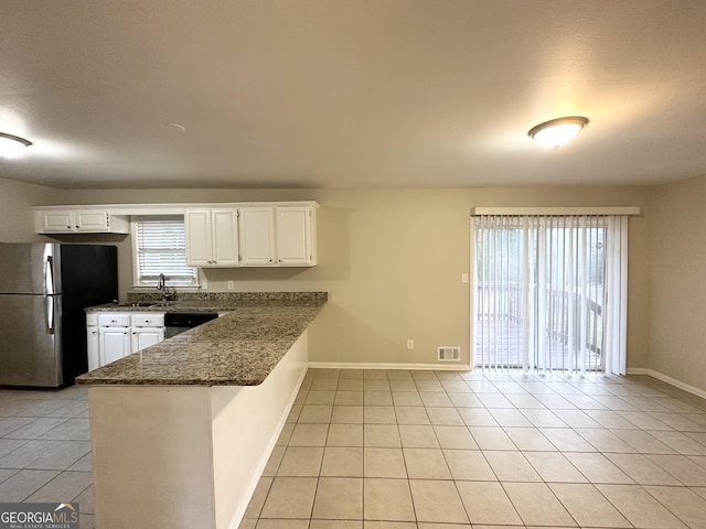 kitchen with light tile patterned floors, kitchen peninsula, appliances with stainless steel finishes, dark stone countertops, and white cabinets