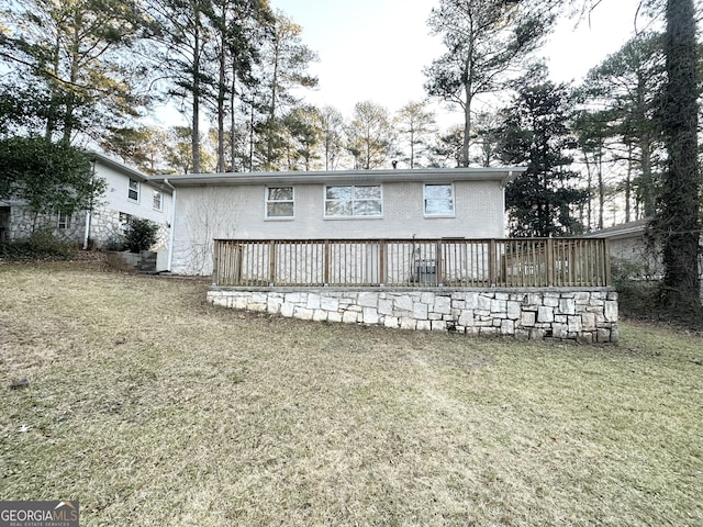 rear view of property with a wooden deck and a lawn