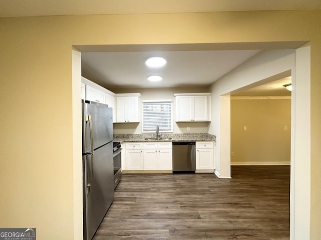 kitchen with appliances with stainless steel finishes, sink, white cabinetry, and dark hardwood / wood-style floors