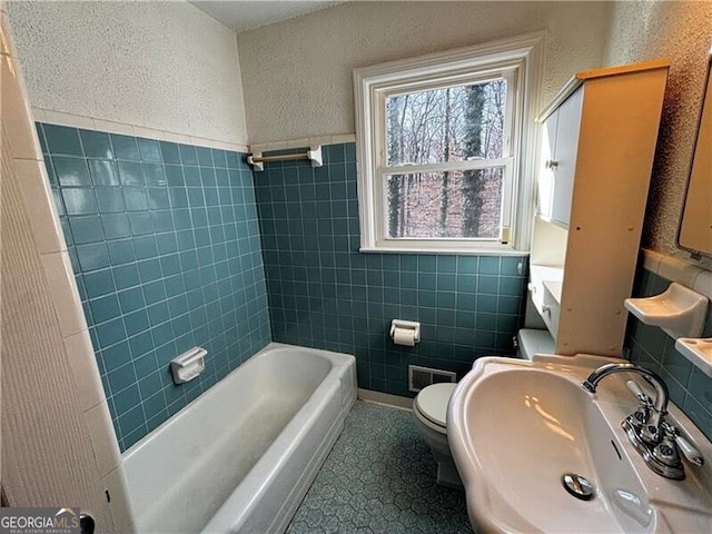 full bathroom featuring toilet, tile walls, tile patterned floors, sink, and shower with separate bathtub