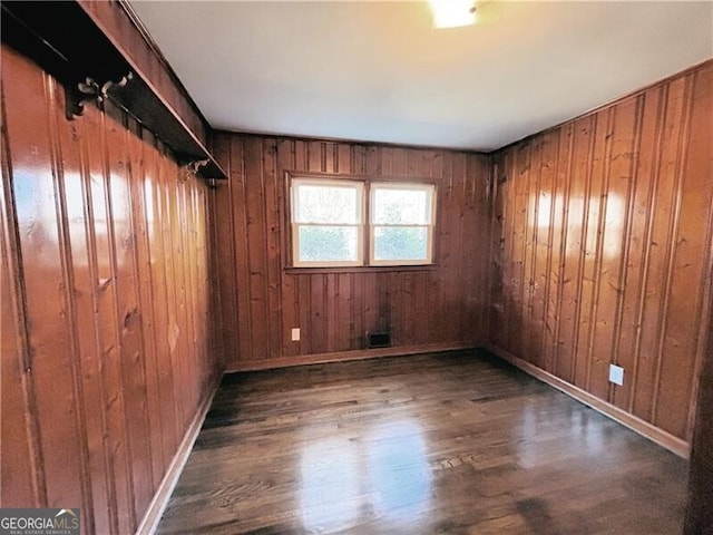 spare room featuring dark hardwood / wood-style floors and wooden walls