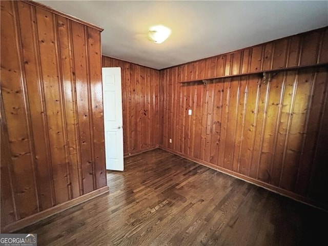 unfurnished room with dark wood-type flooring and wood walls