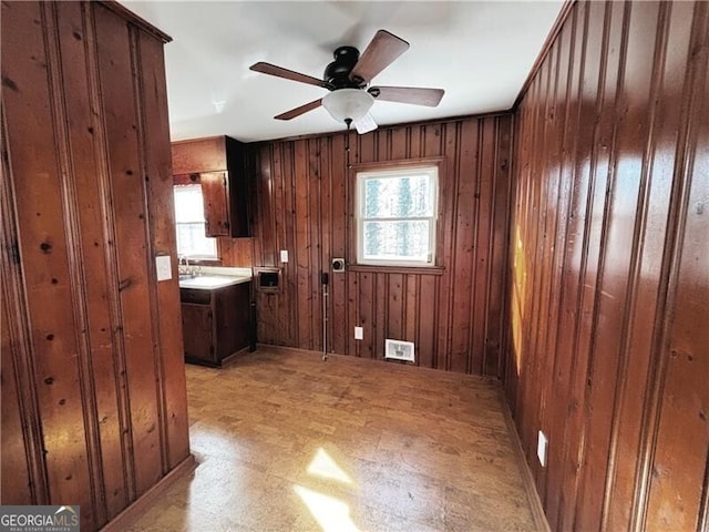 interior space featuring ceiling fan, a wealth of natural light, and wooden walls