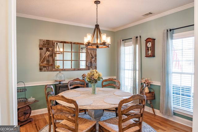 dining area featuring light hardwood / wood-style floors, ornamental molding, and a chandelier