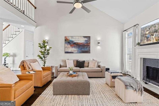 living room featuring high vaulted ceiling, ceiling fan, a tile fireplace, and hardwood / wood-style flooring